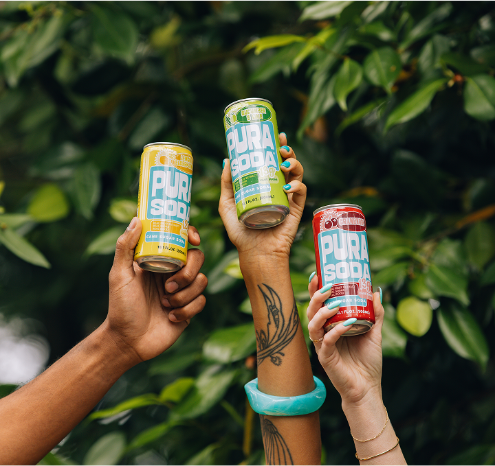 people holding up cans of Pura Soda